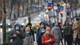People walk wearing masks during an anti-pollution protest outside the city hall in Bucharest, Romania, Wednesday, Dec. 12, 2018.