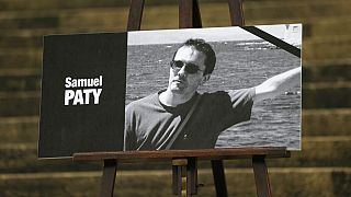 The portrait of slain teacher Samuel Paty with a black ribbon is displayed Tuesday, Oct.20, 2020 on the steps of the National Assembly in Paris.