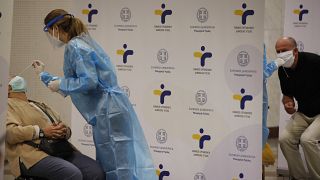 A medical worker wearing protective gear collects a swab from a commuter during rapid tests for COVID-19 at Syntagma station