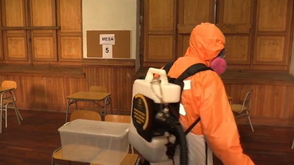 Un trabajador desinfectando un centro de votación en Santiago Un trabajador desinfectando un centro de votación en Santiago