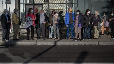 Personas esperan en una parada de bus de Barcelona