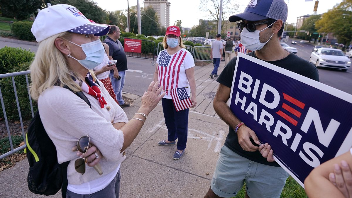 A Donald Trump supporter, left, and a Joe Biden supporter, right, discuss political issues in front of Belmont University in Nashville, Tenn.