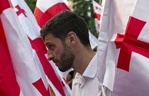 An opposition demonstrator stands between Georgian flags during a rally in front of the Georgian Parliament's building in Tbilisi, Georgia, Saturday, July 6, 2019.