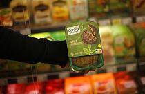 A store clerk shows a plant based burger at a supermarket chain in Brussels, Friday, Oct. 23, 2020. 