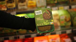 A store clerk shows a plant based burger at a supermarket chain in Brussels, Friday, Oct. 23, 2020. 