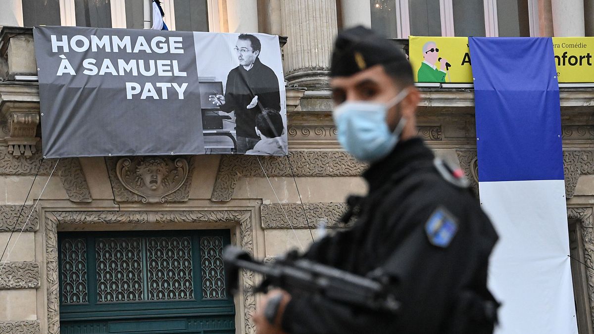 A police officer next to a portrait of murdered French teacher Samuel Paty