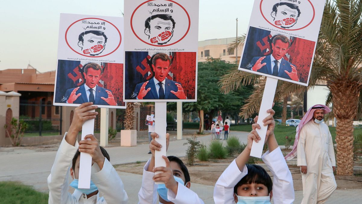 أطفال كويتيون يرفعون لافتات تعبر عن غضبهم من الرئيس الفرنسي إيمانويل ماكرون 
