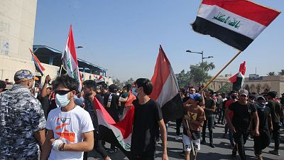 متظاهرون عراقيون يلوحون بالأعلام أثناء تجمعهم في ساحة التحرير وسط العاصمة بغداد، 25 أكتوبر / تشرين الأول 2020