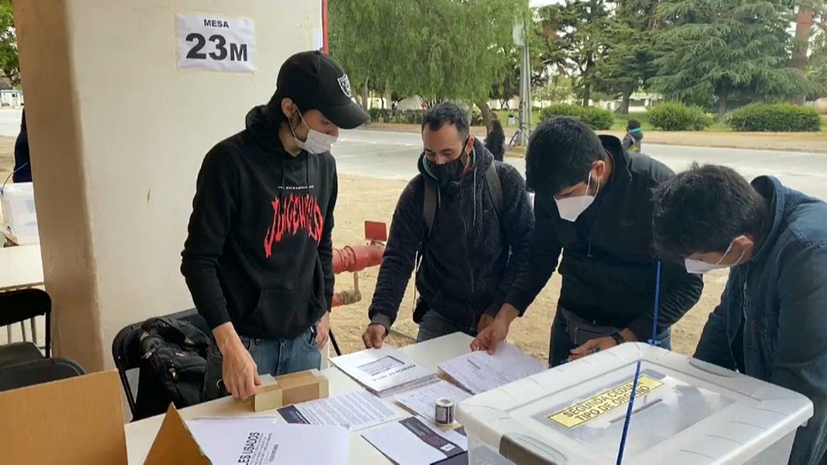 Un grupo de jóvenes revisa las listas en un colegio electoral a cielo abierto