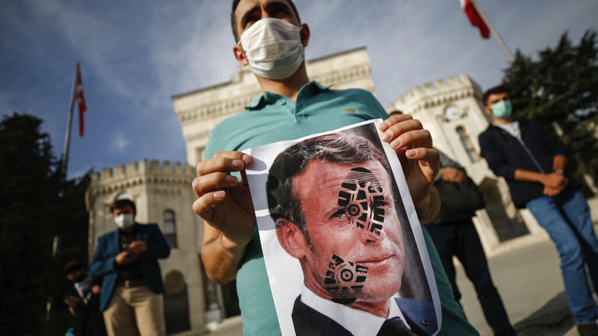 A youth holds a photograph of France's President Emmanuel Macron, stamped with a shoe mark, during a protest against France in Istanbul, Sunday, Oct. 25, 2020.