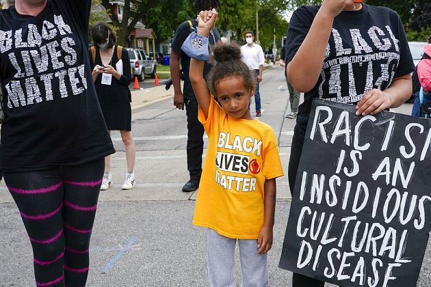 Six-year-old Deja holds her hand in the air during a Black Lives Matter protest Tuesday, Sept. 1, 2020, in Kenosha, Wis. 