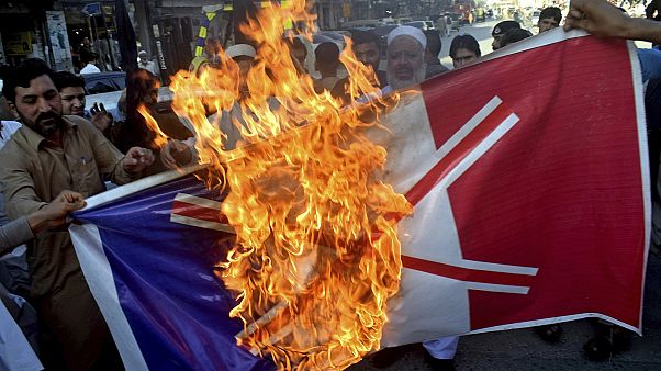 Traders burn burn a French flag during a protest against the publishing of caricatures of the Prophet Muhammad in Peshawar, Pakistan, on Monday, October 26, 2020. Traders burn burn a French flag during a protest against the publishing of caricatures of the Prophet Muhammad in Peshawar, Pakistan, on Monday, October 26, 2020.