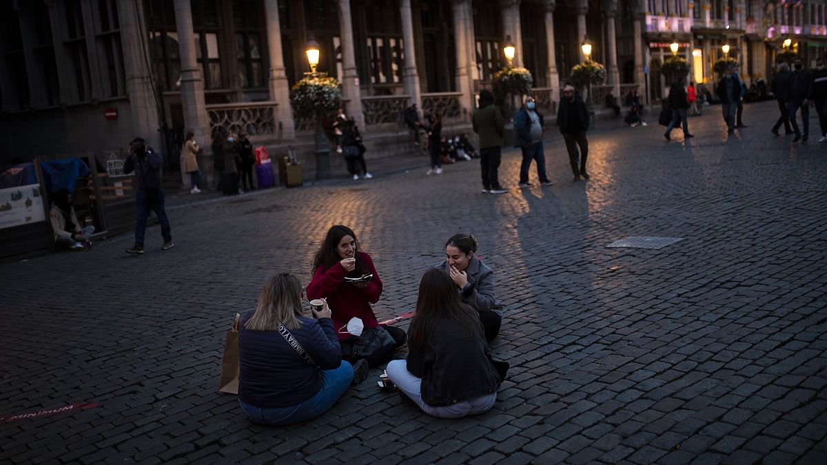 Students sit and eat waffles on Grand Place during an autumn evening prior to the curfew in downtown Brussels, Oct. 23, 2020. 