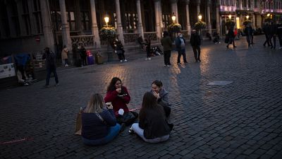 Students sit and eat waffles on Grand Place during an autumn evening prior to the curfew in downtown Brussels, Oct. 23, 2020. 