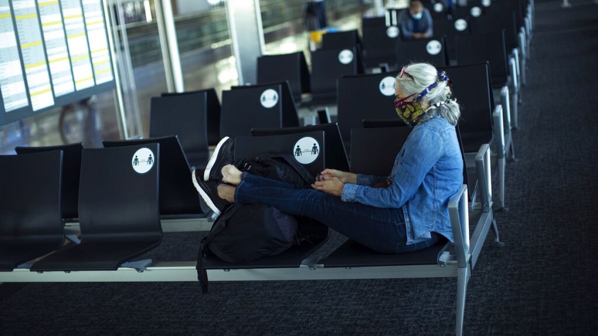 A passenger, wearing a face mask to protect against the spread of coronavirus, sits before boarding her flight at the Zaventem international airport