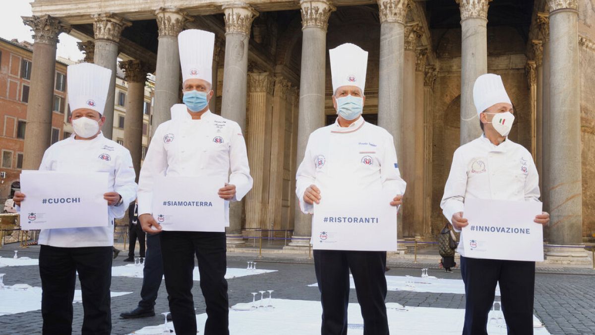 Cozinheiros em protesto em frente ao panteão de Roma com as mensagem "#cozinheiros", "#estamos por terra", "#restaurantes" e "#inovação"