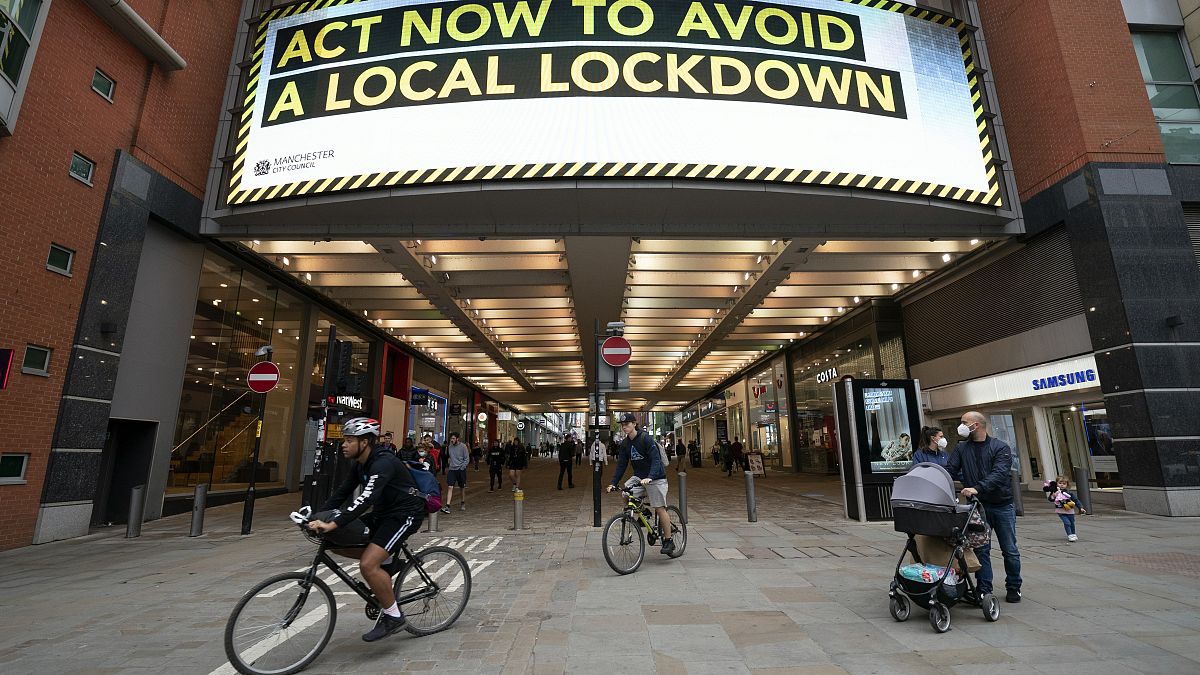 Members of the public are seen by a public information message in Manchester, England. 