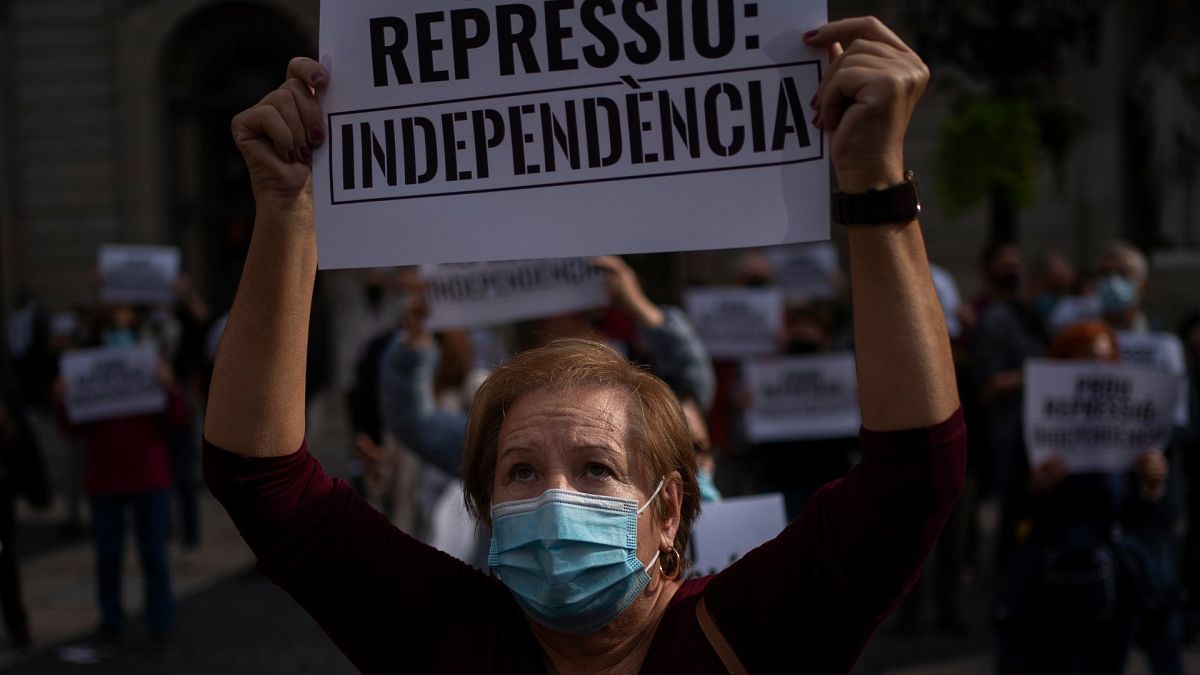 متظاهرة كتالونية ترفع لافتة كتب عليها "أوقفوا القمع" بعد اعتقال 21 شخصاً يشبته بتورطهم بهدر المال العام 