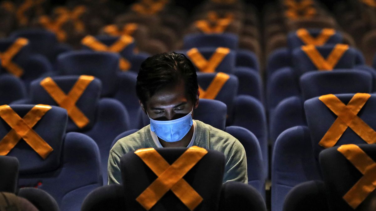 رجل يراقب هاتفه داخل قاعة سينما في العاصمة الاندونيسية جاكارتا حيث وضعت على المقاعد علامات التباعد الاجتماعي. 2020/10/23 