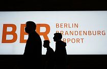 People walk in front of a sign of the new Berlin-Brandenburg-Airport 'Willy Brandt' in inside the Terminal 1, 27 Oct 2020
