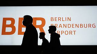 People walk in front of a sign of the new Berlin-Brandenburg-Airport 'Willy Brandt' in inside the Terminal 1, 27 Oct 2020