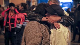 People hug outside the Colectiv nightclub, the scene of a fire which killed 64, during a commemoration in Bucharest, Romania, Friday, Oct. 27, 2017. 