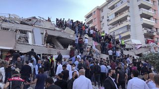 Люди собрались у обломков рухнувшего здания в Измире.