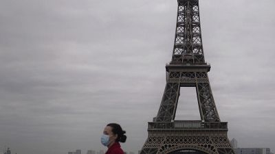 Une femme masquée marche à Paris, à proximité de la Tour Eiffel, le 30 octobre 2020, Paris, France