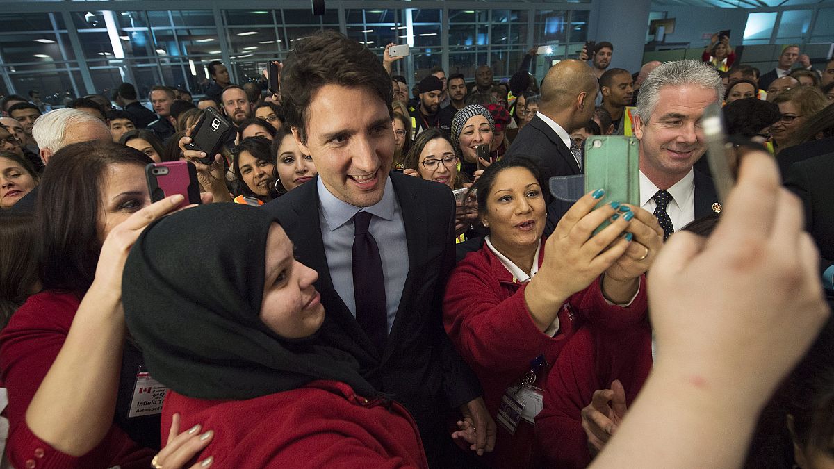 Canadian Prime Minister Justin Trudeau, centre, poses for a selfies with workers before he greets refugees from Syria at Pearson International airport, in Toronto