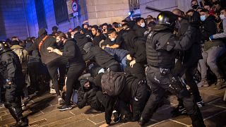 Police uses batons to disperse protesters during clashes in downtown Barcelona, Spain, Friday, Oct. 30, 2020. 