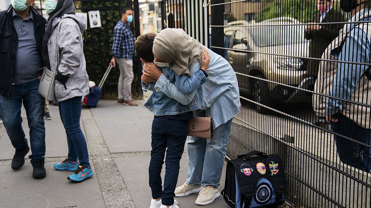 A woman, wearing a face mask to fight against the spread of the coronavirus, hugs her child before entering the Heembeek primary school during the first day of classes in Brus
