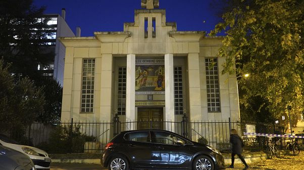 A woman walks past the Greek Orthodox church after a priest was shot Saturday Oct.31, 2020