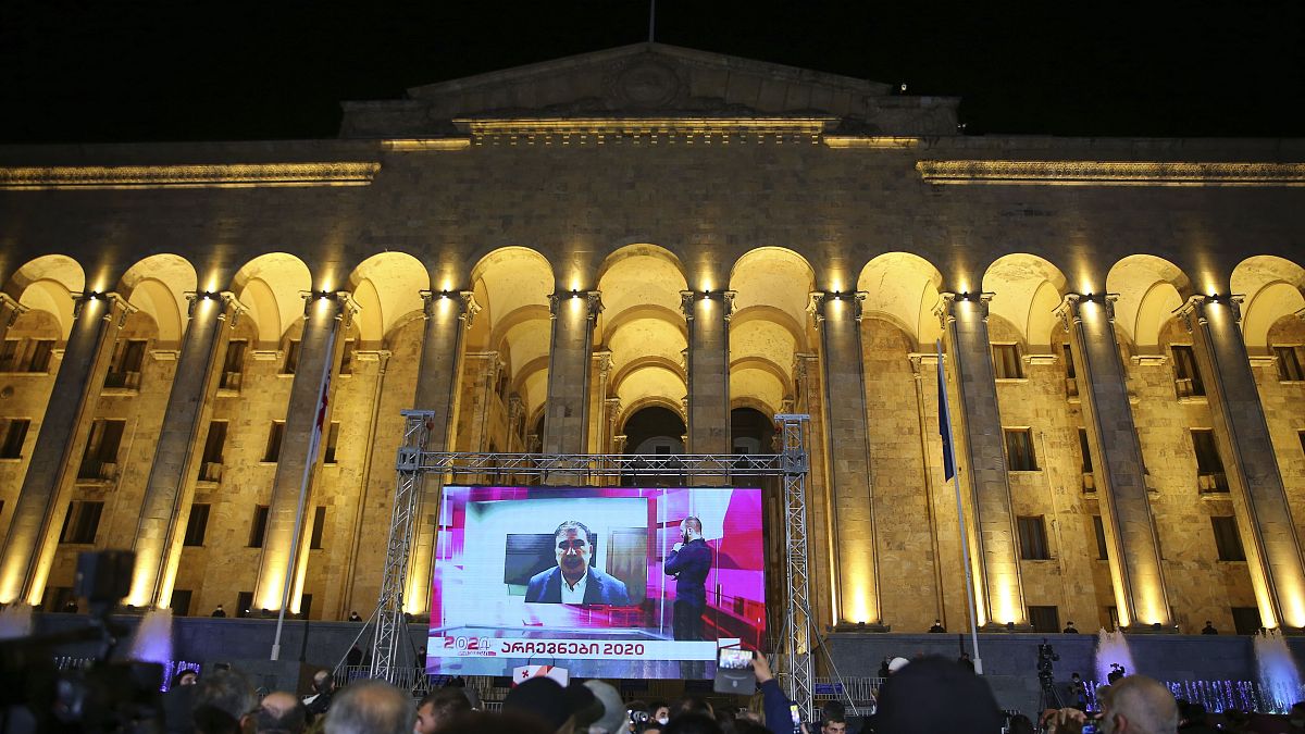 Supporters of Georgian ex-President Mikheil Saakashvili's United National Movement watch his address on a big screen in front of the Parliament's building after the parliament