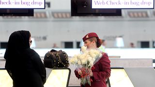 A Qatar Airways employee greets a Qatari passenger with flowers on the occasion of the opening of the new Hamad International Airport in Doha, Qatar, Tuesday, May 27, 2014
