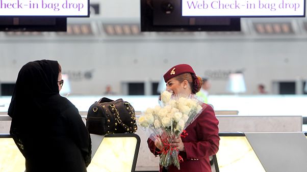 A Qatar Airways employee greets a Qatari passenger with flowers on the occasion of the opening of the new Hamad International Airport in Doha, Qatar, Tuesday, May 27, 2014 A Qatar Airways employee greets a Qatari passenger with flowers on the occasion of the opening of the new Hamad International Airport in Doha, Qatar, Tuesday, May 27, 2014