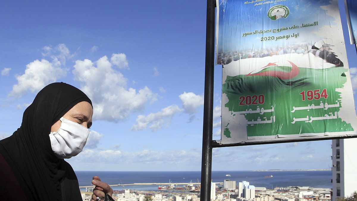 A woman walks past posters promoting the vote for the upcoming referendum, Tuesday, Oct.27, 2020 in Algiers
