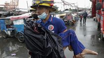A rescuer carries a sick child as they evacuate residents living along a coastal community in Manila, Philippines on Sunday, Nov. 1, 2020.