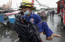 A rescuer carries a sick child as they evacuate residents living along a coastal community in Manila, Philippines on Sunday, Nov. 1, 2020. 