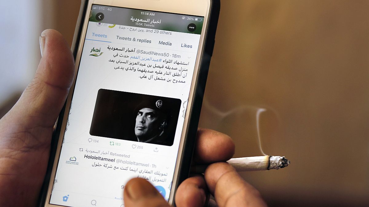 A man reads Saudi news on Twitter fronted by a picture of the prominent bodyguard to Saudi Arabia's King Salman Maj. Gen. Abdulaziz al-Fagham, at a coffee shop, in Jiddah