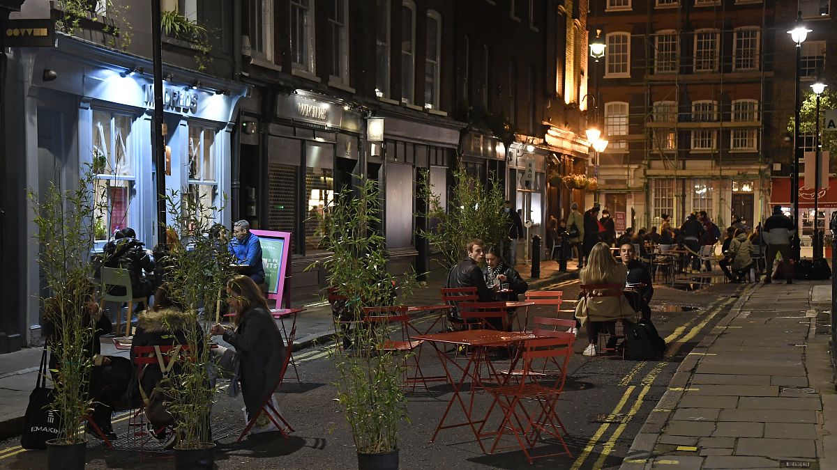 People dine outside on a street in central London, Saturday, Oct. 31, 2020. 