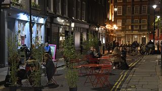 People dine outside on a street in central London, Saturday, Oct. 31, 2020. 