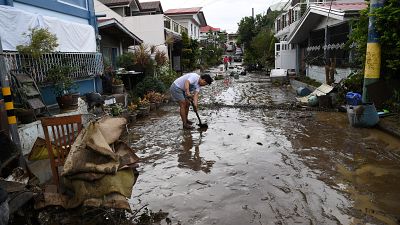 A resident shovels mud from a neighbourhood street following flooding in Batangas City.