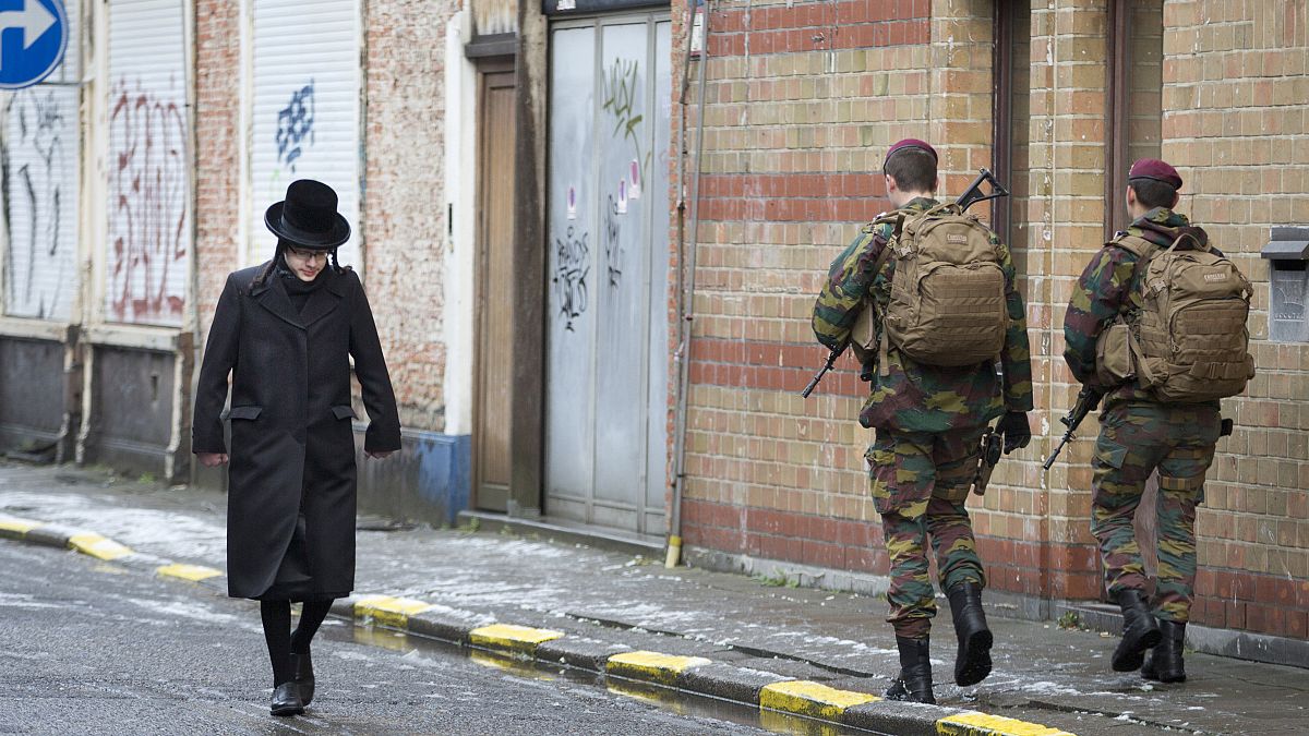 رجل من الجالية اليهودية يسير بجوار جنود بلجيكيين أثناء قيامهم بدورية في أنتويرب، بلجيكا /24 يناير-2015.