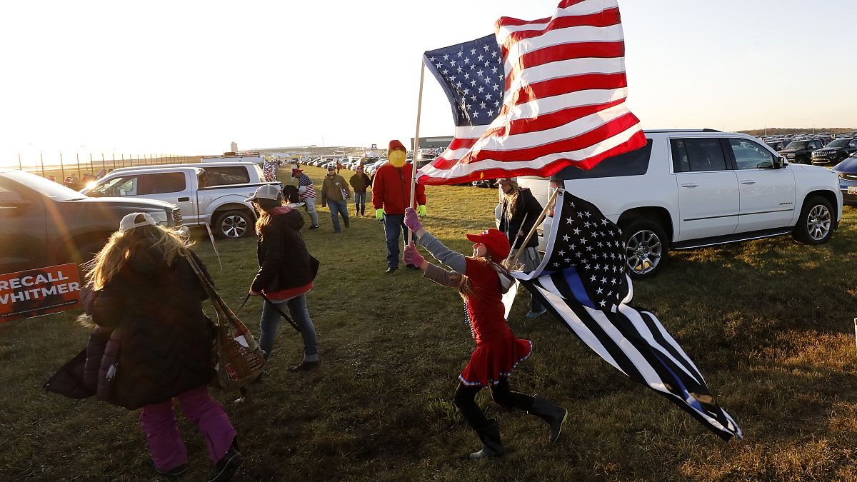 A young woman plays with flags as supporters of US President Donald Trump arrive to attend his final Make America Great Again rally