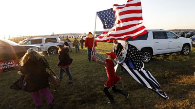 A young woman plays with flags as supporters of US President Donald Trump arrive to attend his final Make America Great Again rally