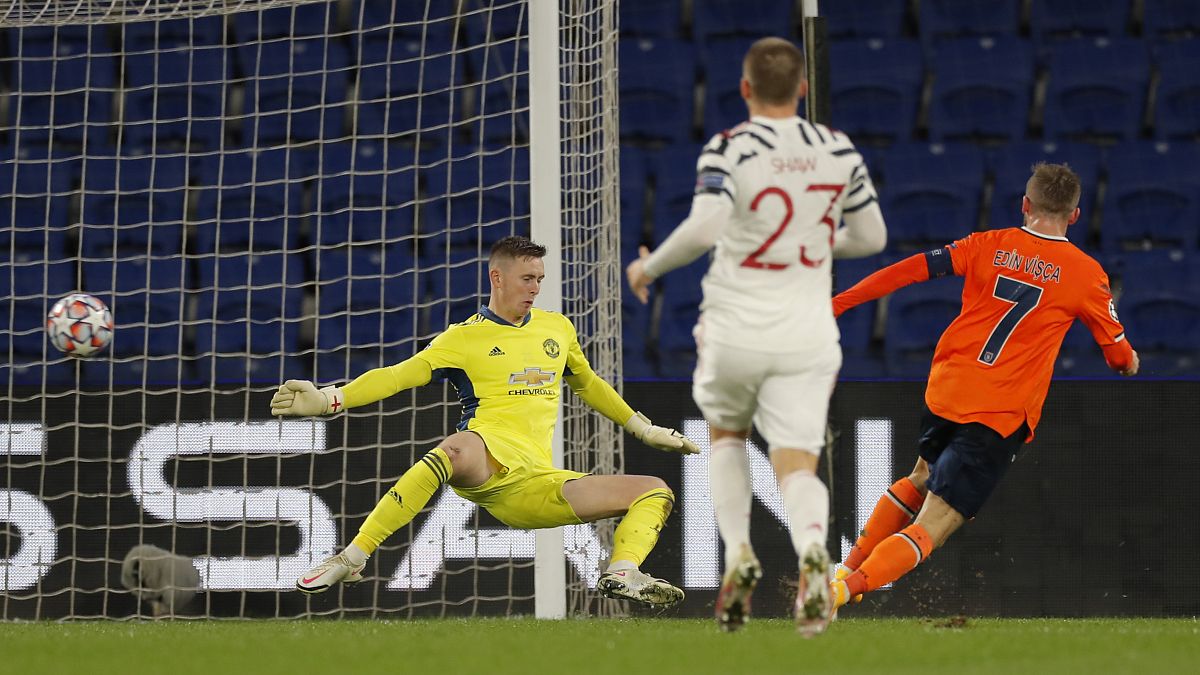 Manchester United's goalkeeper Dean Henderson, left, fails to save the ball as Basaksehir's Edin Visca, right, scores his side's second goal in the Champions League.