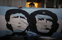 A soccer fan stands behind a banner featuring former soccer star Diego Maradona and Marxist revolutionary Ernesto "Che" Guevara, outside the Clinica Olivos, where Maradona wil