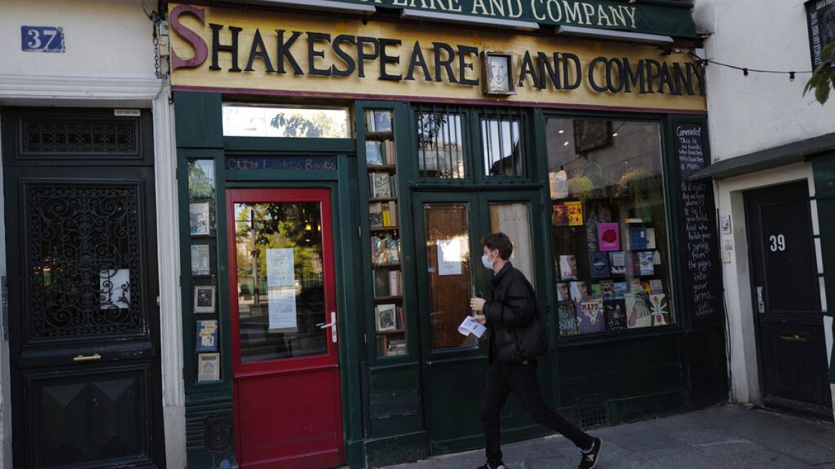 A man walks by the closed English and American literature Shakespeare and Co. bookstore in Paris, France, Thursday, Nov. 05, 2020.