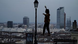 A woman balances on a railing on a hill above Lyon, France, which is in a monthlong partial lockdown
