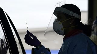 University of Washington research coordinator Rhoshni Prabhu holds up a swab after testing a passenger at a free COVID testing site in Seattle.